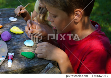 Painting stones becomes an act of sharing, as children craft vibrant, imaginative DIY gifts for special people. 136662017
