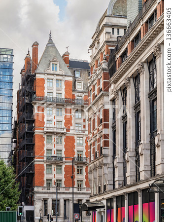 Classic British architecture lines a traditional London street, with red brick buildings and historic facades beneath a cloudy sky. Classic British architecture lines a traditional London street, with red brick buildings and historic facades beneath a cloudy sky. 136663405