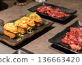 Multiple dishes served on dark plates including spicy salmon and raw meat. The table setting represents modern restaurant dining experience. 136663420