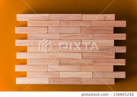 Wooden building blocks arranged in a rectangular pattern on a vibrant orange background, showcasing natural wood grain and smooth surfaces Wooden building blocks arranged in a rectangular pattern on a vibrant orange background, showcasing natural wood grain and smooth surfaces 136665288