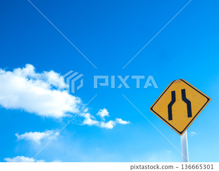 一幅風景畫，藍天白雲，路牌上寫著「前方道路狹窄」。 136665301