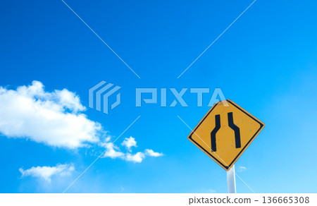 一幅風景畫，藍天白雲，路牌上寫著「前方道路狹窄」。 136665308