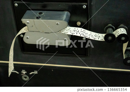 A hole punch makes holes in a paper strip A hole punch makes holes in a paper strip 136665354