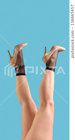 Nude patent high heels with black fishnet ankle socks on blue background. Nude patent high heels with black fishnet ankle socks on blue background. 136665457