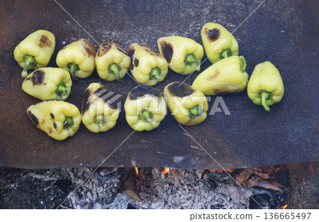 ripe bell peppers are fried on a sheet of iron over an open fire ripe bell peppers are fried on a sheet of iron over an open fire 136665497