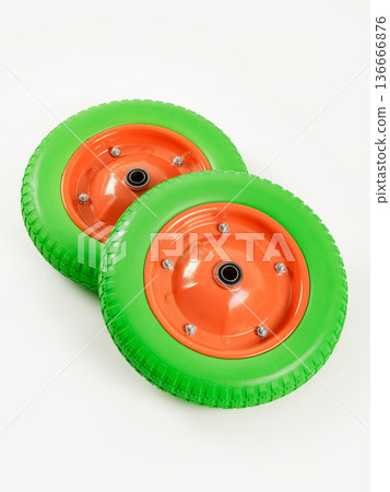 Two wheels from a garden cart on a white background. Green rubber, orange disc. Two wheels from a garden cart on a white background. Green rubber, orange disc. 136666876