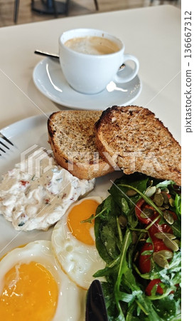 Healthy breakfast with fried egg, toast, vegetable salad and cream spread served with coffee on table. Morning meal concept symbolizing nutrition, balance and energy Healthy breakfast with fried egg, toast, vegetable salad and cream spread served with coffee on table. Morning meal concept symbolizing nutrition, balance and energy 136667312