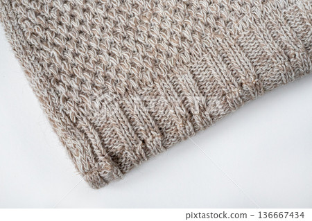 Folded knitted gray wool blanket. Edge of the gray knitted blanket on a white background. Top view 136667434