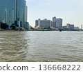 Scenic view of the Chao Phraya River in Bangkok with reflections of tall buildings and boats cruising along the water captured from the center in 2024 136668222