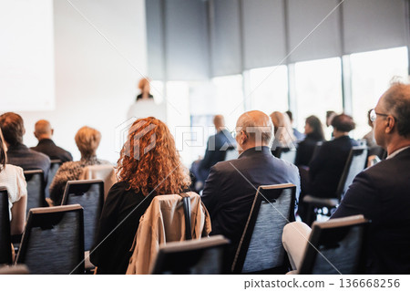 Business and entrepreneurship symposium. Female speaker giving a talk at business meeting. Audience in conference hall. Rear view of unrecognized participant in audience. Business and entrepreneurship symposium. Female speaker giving a talk at business meeting. Audience in conference hall. Rear view of unrecognized participant in audience. 136668256