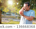 Overweight man suffering from elbow pain while exercising in park. Concept of joint inflammation, tendonitis, sports injury, tennis elbow, orthopedic problem and healthcare for obese people workout. 136668368