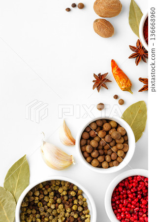 Spices and herbs on a white surface with bowls and ingredients displayed in a clean layout Spices and herbs on a white surface with bowls and ingredients displayed in a clean layout 136668960