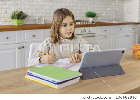 Child completing schoolwork with tablet at kitchen table in cozy modern home Child completing schoolwork with tablet at kitchen table in cozy modern home 136668986