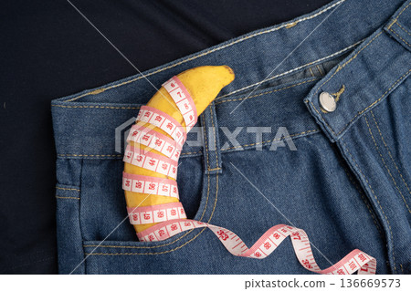Banana with measuring tape on jean trousers, penis health. Banana with measuring tape on jean trousers, penis health. 136669573