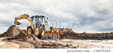A universal excavator loader moves sand at a construction site. Excavation work at a construction site for a future project A universal excavator loader moves sand at a construction site. Excavation work at a construction site for a future project 136670269