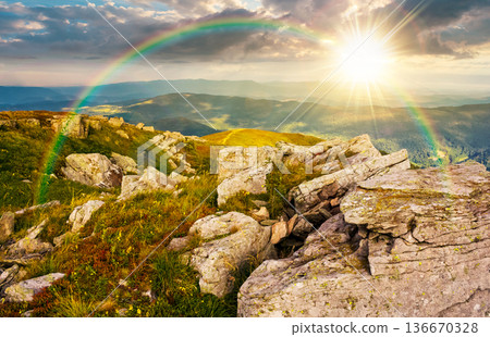 huge rocky formations on a grassy hill at sunset. wonderful mountain landscape in august in evening light. alpine scenery on a cloudy weather under the rainbow. spectacular view in to the distance huge rocky formations on a grassy hill at sunset. wonderful mountain landscape in august in evening light. alpine scenery on a cloudy weather under the rainbow. spectacular view in to the distance 136670328