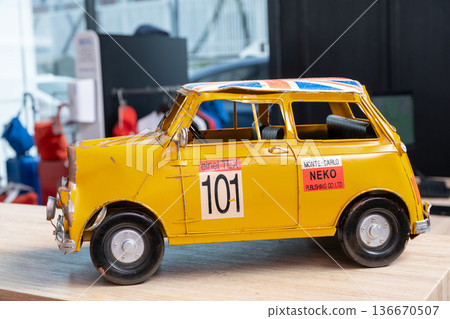 Unique miniature yellow Mini Cooper car displayed in a BMW salon showcases craftsmanship and design excellence Unique miniature yellow Mini Cooper car displayed in a BMW salon showcases craftsmanship and design excellence 136670507