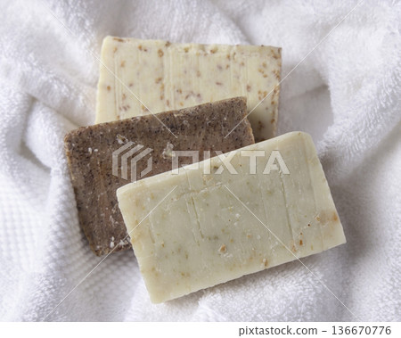 Unbranded beige and brown solid soap bars on white terry towel, bathroom spa amenities 136670776