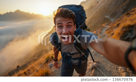 A jubilant hiker captures a handheld vlog selfie atop a mountain ridge at sunrise. Excited male carrying a large backpack smiling breathlessly at the camera, with face glowing with sweat A jubilant hiker captures a handheld vlog selfie atop a mountain ridge at sunrise. Excited male carrying a large backpack smiling breathlessly at the camera, with face glowing with sweat 136670976