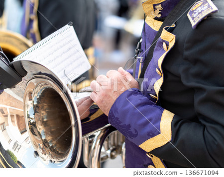 Close up of a musician in purple and gold uniform playing a brass instrument Close up of a musician in purple and gold uniform playing a brass instrument 136671094