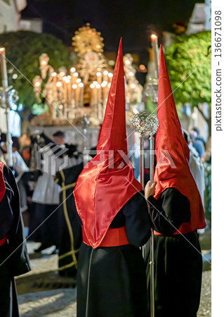 Many nazarenos with red hoods walking in procession Many nazarenos with red hoods walking in procession 136671098