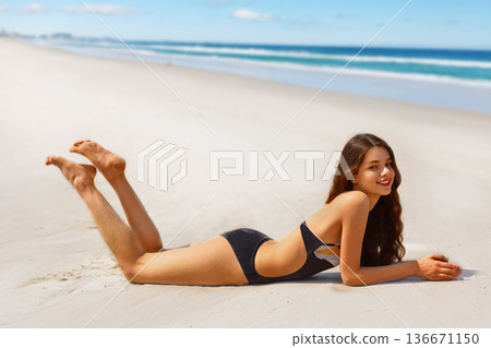Portrait of gorgeous young woman smiling while relaxing on beach Portrait of gorgeous young woman smiling while relaxing on beach 136671150