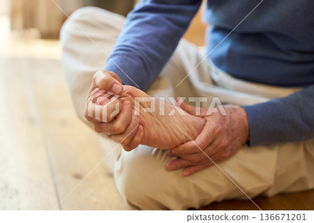 Senior Asian man holding his sore soles Senior Asian man holding his sore soles 136671201