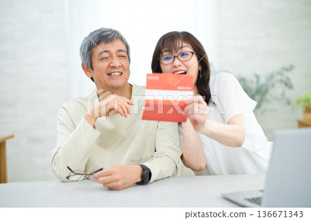 A couple in their 60s looking at their savings passbook in the living room 136671343
