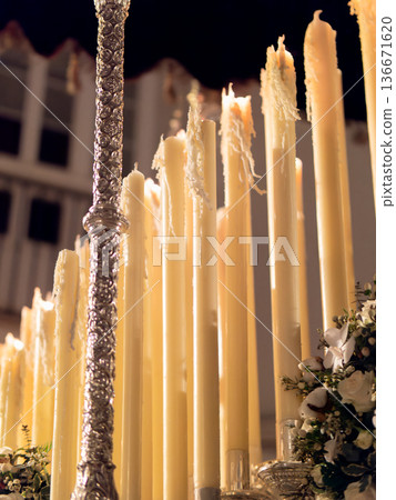 Close up of many tall wax candles burning on a religious processional float at night 136671620