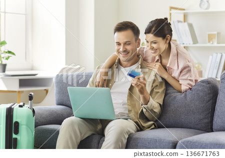 Couple using laptop and credit card for online travel booking at home together Couple using laptop and credit card for online travel booking at home together 136671763