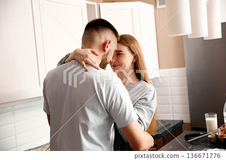 Couple shares a moment in the kitchen while cooking together in a modern home during the afternoon Couple shares a moment in the kitchen while cooking together in a modern home during the afternoon 136671776