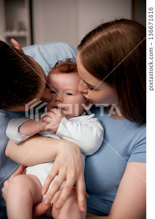 Couple shares love while holding their baby in a home setting in the evening, creating a warm family moment together, capturing joy and connection Couple shares love while holding their baby in a home setting in the evening, creating a warm family moment together, capturing joy and connection 136671816