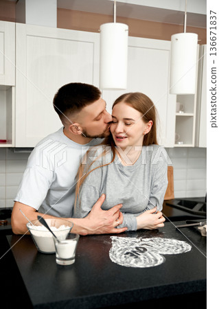 Couple enjoys cooking together in kitchen while sharing a moment of affection and connection at home in morning Couple enjoys cooking together in kitchen while sharing a moment of affection and connection at home in morning 136671837