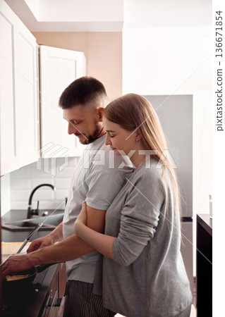 Couple prepares food together in kitchen while enjoying each others company during a morning routine Couple prepares food together in kitchen while enjoying each others company during a morning routine 136671854