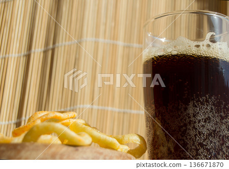 Plate of chips, a glass of dark beer with foam, bubbles on wooden background 136671870