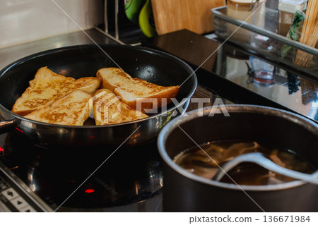 Freshly baked French toast for breakfast. Kitchen scene with frying pan cooking. Freshly baked French toast for breakfast. Kitchen scene with frying pan cooking. 136671984