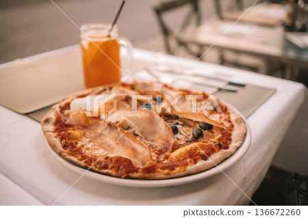 Italian pizza and orange juice on outdoor restaurant table 136672260
