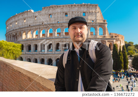 Handsome 30s tourist visiting Colosseum in Rome, Italy. Young man taking photo in front of famous Italian landmark  136672272