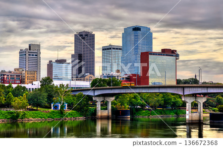 Little Rock skyline in Arkansas. Downtown city view features the Main Street Bridge with a yellow streetcar crossing the Arkansas River near Riverfront Park under a cloudy sky Little Rock skyline in Arkansas. Downtown city view features the Main Street Bridge with a yellow streetcar crossing the Arkansas River near Riverfront Park under a cloudy sky 136672368
