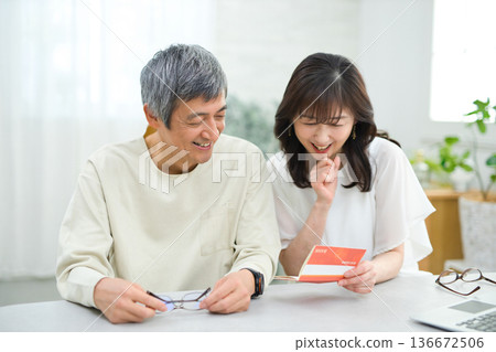 一對六十多歲的夫婦正在客廳裡查看他們的儲蓄存摺。 136672506