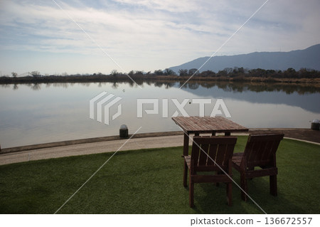 Wooden tables and chairs set up by a scenic lake 136672557