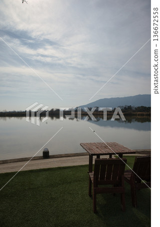 Wooden tables and chairs set up by a scenic lake 136672558