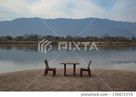 Wooden tables and chairs set up by a scenic lake 136672559
