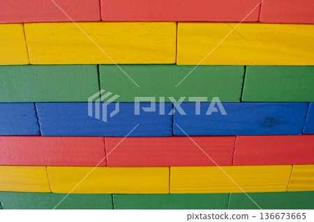 Close-up of a wall made from brightly colored wooden toy blocks arranged in a neat geometric pattern and texture, suitable for a background 136673665