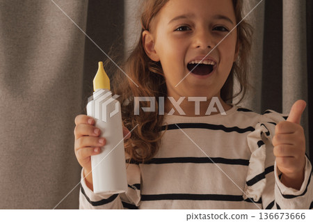 Smiling while using a nasal spray and giving a confident thumbs up sign 136673666