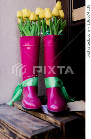 pair of bright pink rain boots with yellow tulips. pair of bright pink rain boots with yellow tulips. 136674339
