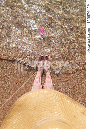 Women's feet in the sand and sea waves on the beach, top view Women's feet in the sand and sea waves on the beach, top view 136674439