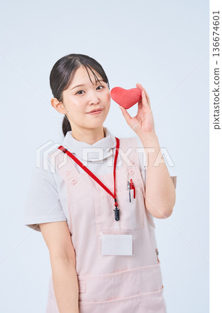 一個穿著白大褂和圍裙的年輕女子 136674601