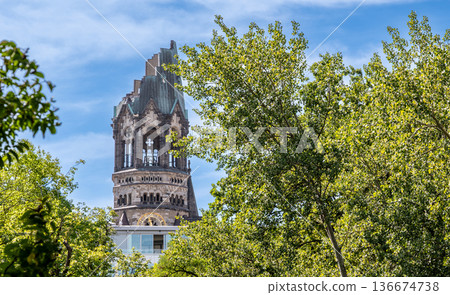 Berlin, germany, august 14,2023. Kaiser wilhelm memorial church tower, known as a berlin landmark and symbol of peace, rising above green trees on a sunny day Berlin, germany, august 14,2023. Kaiser wilhelm memorial church tower, known as a berlin landmark and symbol of peace, rising above green trees on a sunny day 136674738