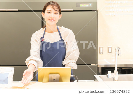 一位年輕的女店員在收銀台前提供指導。 一位年輕的女店員在收銀台前提供指導。 136674832